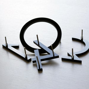 May include: Black acrylic numbers and a circle, each with a small metal pin on the back for hanging. The numbers are 4, 2, and 4.