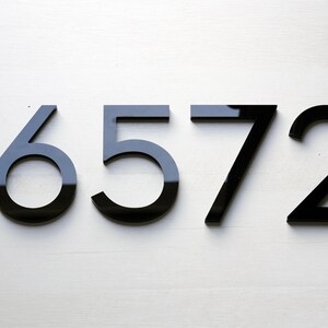 May include: Black house numbers on a white wall, reading 16572.
