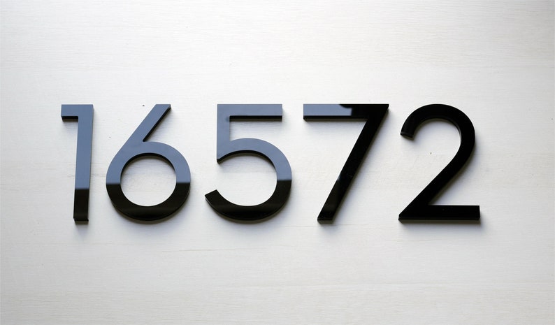 May include: Black house numbers on a white wall, reading 16572.