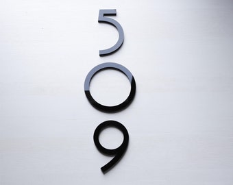 Può includere: Numeri 509 in acrilico nero, disposti verticalmente, su uno sfondo bianco.