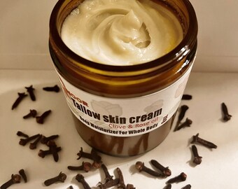 以下が含まれることがあります： 白いラベルに「Tallow Skin Cream Clove & Rose oil Deep Moisturizer For Whole Body」と書かれた、茶色のガラス瓶に入った牛脂のスキンクリーム。瓶は茶色のクローブで囲まれています。