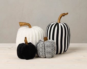 May include: Four decorative pumpkins in black and white. One pumpkin is white with a fuzzy texture, one is black velvet, one is white with black lace, and one is black and white striped.