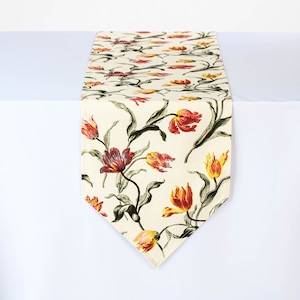 Könnte beinhalten: Ein weißer Tischläufer mit einem floralen Muster mit roten, orangefarbenen und gelben Tulpen auf cremefarbenem Hintergrund.