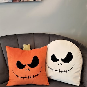 May include: Two Halloween themed throw pillows. One pillow is orange with a black Jack Skellington face and the other is white with a black Jack Skellington face.