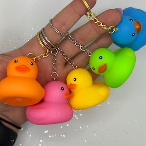 Puede incluir: Cinco llaveros de pato de goma en diferentes colores: naranja, amarillo, rosa, verde y azul. Cada pato tiene un pequeño anillo unido a su espalda para sujetarlo a las llaves.