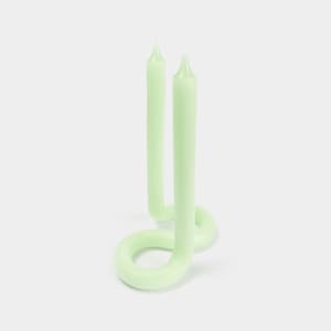 May include: Two light green candles in a twisted, looped shape. The candles are made of wax and have a smooth, matte finish.