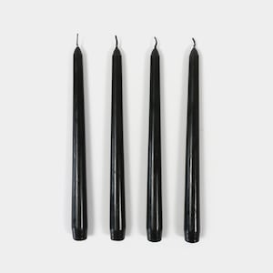 May include: Four black taper candles, each with a pointed tip.