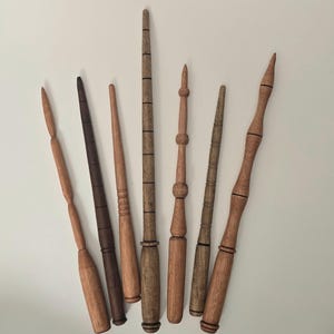 May include: Seven wooden wands of varying lengths and styles. The wands are made of different types of wood and have unique carvings and designs.