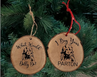 May include: Two wooden Christmas ornaments featuring a portrait of Dolly Parton. One ornament reads "What Would Dolly Do?" and the other reads "I Beg Your Parton".