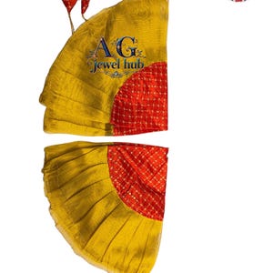 Puede incluir: Dori Pala Rumal de dos piezas, con una vibrante combinación de colores amarillo y rojo. El diseño presenta una forma de abanico con tela amarilla plisada y un centro rojo estampado. El texto "Dori Pala Rumal" y "Sagan collection Rumal" son visibles.