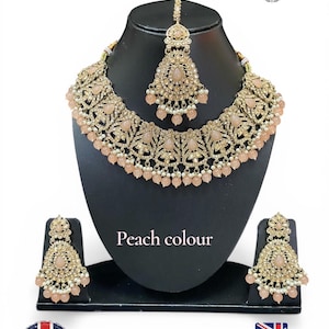 Peut inclure: Un ensemble de bijoux couleur pêche, comprenant un collier, des boucles d'oreilles et un serre-tête, présenté sur un mannequin noir. L'ensemble présente une filigrane dorée complexe et des perles de couleur pêche. Le texte "Peach colour" est visible.