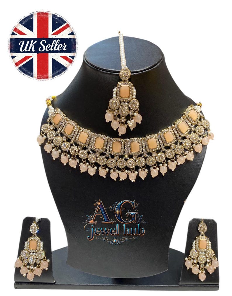 May include: A peach-colored and silver-toned jewelry set, including a necklace, earrings, and a headpiece, displayed on a black mannequin. The necklace and earrings feature square peach-colored stones and dangling beads. The set is labeled "UK Seller".