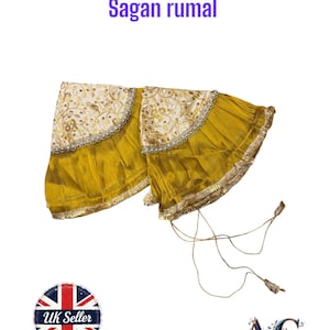 Puede incluir: Un Sangan rumal amarillo y crema, un paño ceremonial indio tradicional. El paño presenta una sección bordada de color crema con detalles dorados y una sección inferior plisada amarilla. El texto "Sagan rumal" se muestra en morado.