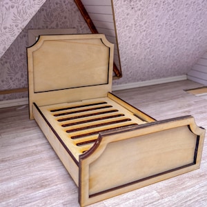 Puede incluir: Una cama de madera para casa de muñecas con un acabado marrón claro y un ribete marrón oscuro. La cama tiene una cabecera y un piecero con un diseño curvo. La cama tiene una base de listones.