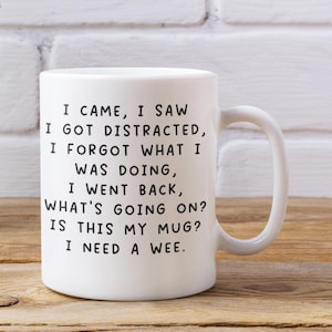 May include: White ceramic mug with a curved handle. The mug features black text that reads: "I CAME, I SAW, I GOT DISTRACTED, I FORGOT WHAT I WAS DOING, I WENT BACK, WHAT'S GOING ON? IS THIS MY MUG? I NEED A WEE."