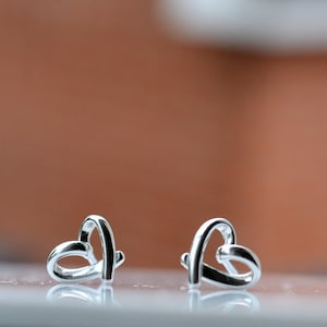 以下が含まれることがあります： 銀製のハート型のイヤリングのペア。イヤリングは、1つの金属片をハート型に曲げて作られています。