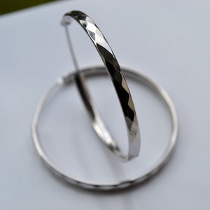 Può includere: Un paio di orecchini a cerchio d'argento con un design testurizzato a forma di diamante.