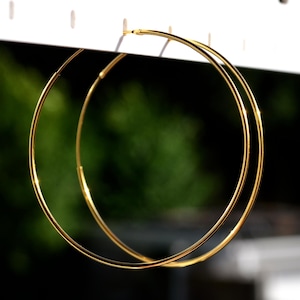 May include: A pair of gold hoop earrings. The hoops are large and have a simple, classic design.