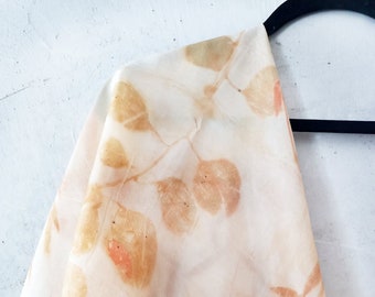 May include: A white silk scarf with a botanical print of leaves in shades of brown and orange.