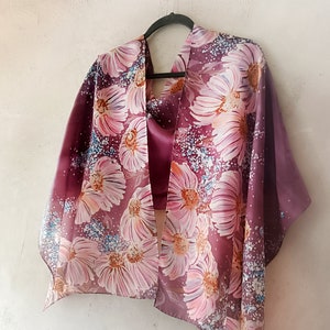 Può includere: Una sciarpa di seta rosa e bordeaux con stampa floreale. La sciarpa presenta un grande motivo floreale astratto con fiori rosa, bianchi e bordeaux.