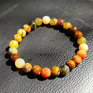 Peut inclure: Un bracelet en perles multicolores avec un dégradé de perles jaunes, orange et rouges. Les perles sont en pierre naturelle et ont une finition polie.