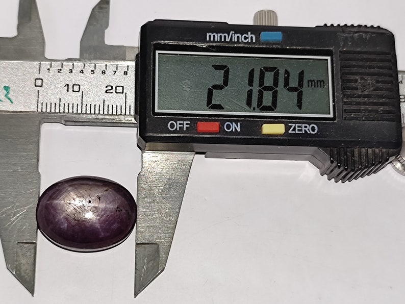 May include: A close-up of a purple gemstone being measured with a digital caliper. The caliper reads 2.184 mm.