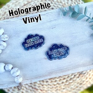 May include: Two holographic vinyl stickers in the shape of a cloud. The stickers are black with white text. The text on the left sticker reads "Certified Black Cloud". The text on the right sticker reads "Black Cloud Energy".