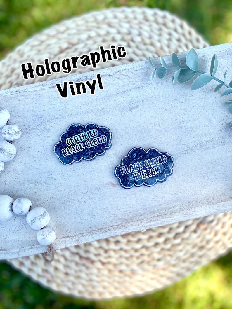 May include: Two holographic vinyl stickers in the shape of a cloud. The stickers are black with white text. The text on the left sticker reads "Certified Black Cloud". The text on the right sticker reads "Black Cloud Energy".