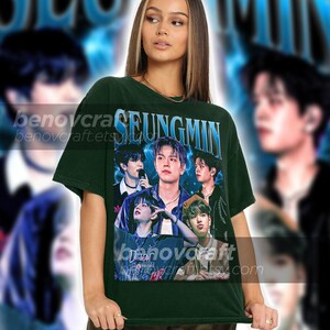 May include: A dark green t-shirt with a graphic print of a K-pop band, featuring the text "SEUNGMIN".