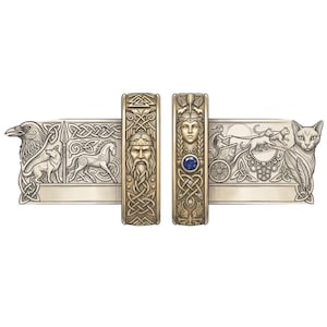 May include: Detailed illustration of two ornate metal bands with Celtic knotwork and figures. One band features a bearded face, the other a woman with a blue gem. The bands are flanked by images of a raven, wolf, horse, cat, and chariot.