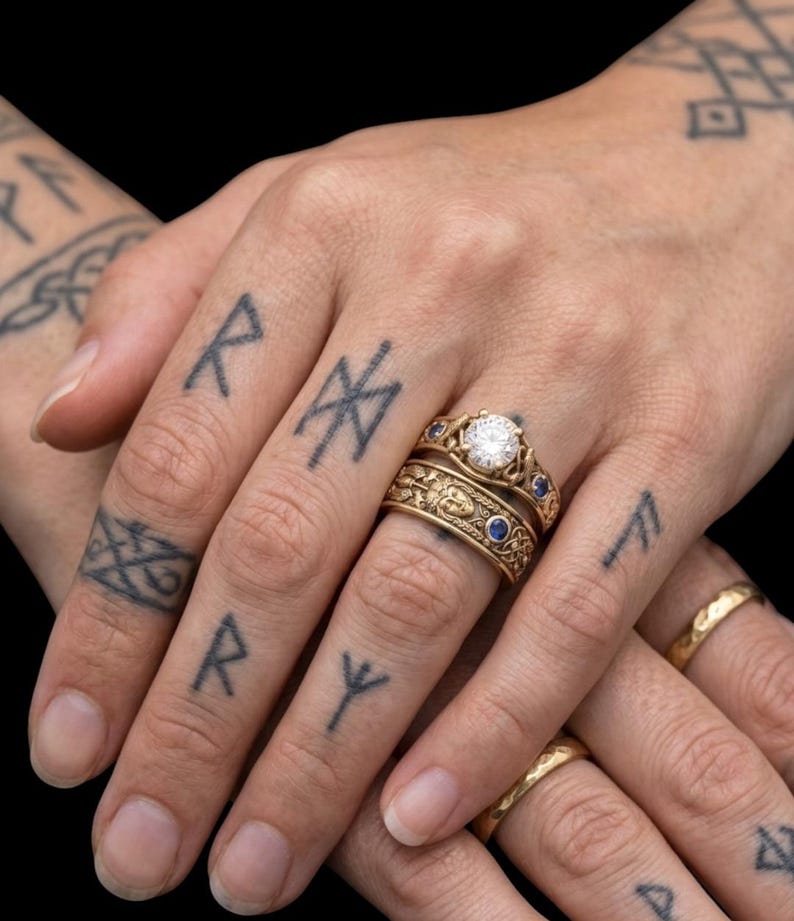 May include: Close-up of multiple gold rings, including a diamond engagement ring and a band with blue gemstones. The rings are on a hand with tattoos of runes and other symbols. The background is black.