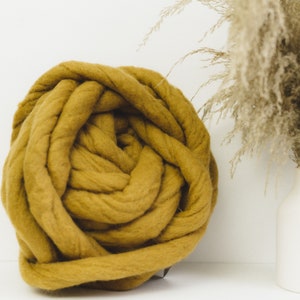 May include: A large ball of mustard yellow chunky yarn, perfect for knitting or crocheting a cozy blanket or throw.
