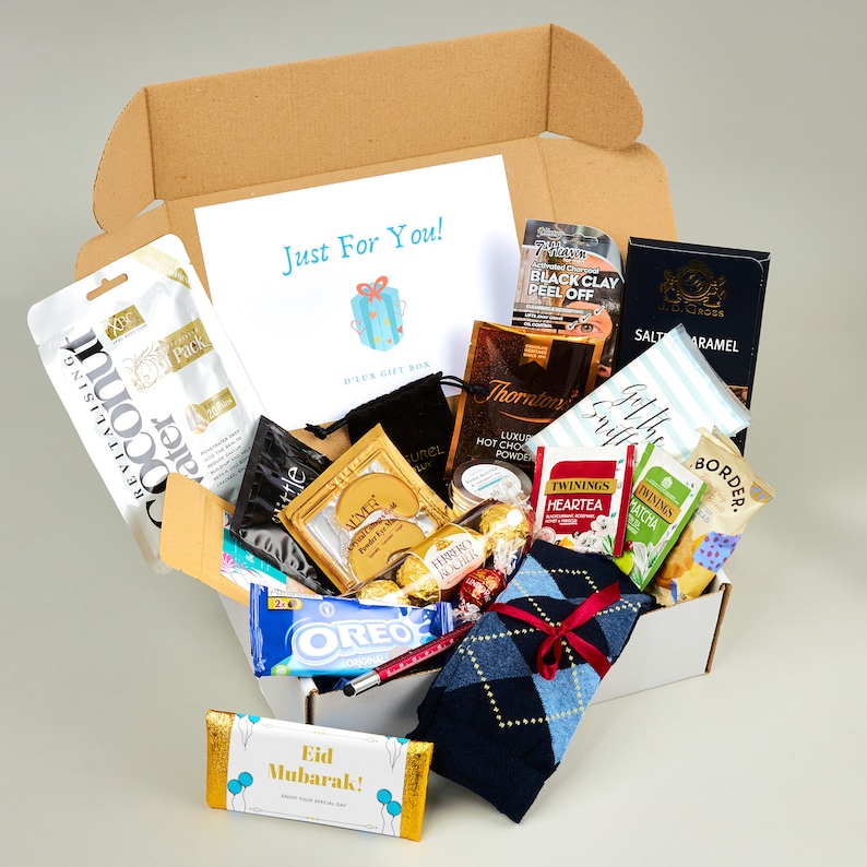 May include: A brown cardboard gift box filled with various items, including a pair of socks, chocolate, tea bags, and beauty products. The box is open and the items are visible. The box has a label that says "Just For You!" and "Deluxe Gift Box".