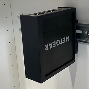 Op de afbeelding: Een zwarte NETGEAR-netwerkswitch gemonteerd op een metalen rek. De switch heeft meerdere ethernetpoorten aan de voorkant.