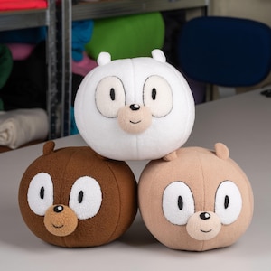 May include: Three plush toys shaped like cartoon animals. The white plush toy has a round body and a black nose. The brown plush toy has a round body and a brown nose. The tan plush toy has a round body and a brown nose.