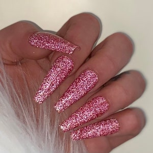 Könnte beinhalten: Lange, pinkfarbene Glitzer-Press-on-Nägel. Die Nägel sind hellrosa mit einem glitzernden Finish.