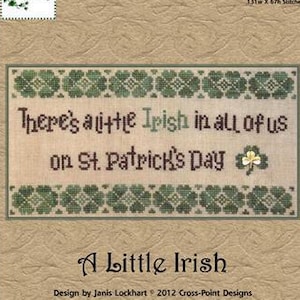 May include: A cross-stitch pattern with the text "There's a little Irish in all of us on St. Patrick's Day." The design includes green shamrocks and a white four-leaf clover. The title "A Little Irish" is below the stitched design.