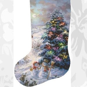 May include: A cross-stitch pattern featuring a Christmas stocking design. The stocking showcases a winter landscape with a decorated Christmas tree and snowmen. The text "Charting Creations presents Stocking Country Shopping" is displayed.