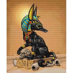 May include: A cross-stitch chart featuring Anubis, the jackal-headed god from Egyptian mythology. The artwork depicts Anubis in black, gold, and blue, seated with a skull and hieroglyphs. The chart is by Stanley Morrison.