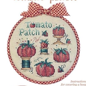 May include: A cross-stitch embroidery kit featuring a tomato patch design. The kit includes a round hoop, fabric, and thread, with a gingham bow at the top. The text "Hoop De Doo" and "tomato patch" are visible.