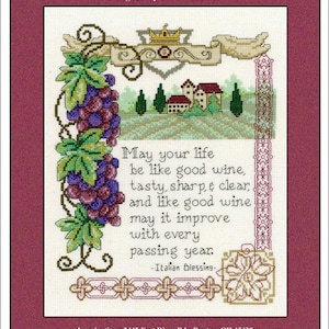 May include: Cross-stitch design titled "Italian Blessing" with a burgundy border. The artwork features a cluster of grapes, a landscape with houses, and text that reads "May your life be like good wine..."