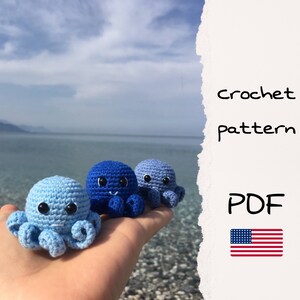 May include: Three crocheted octopus amigurumi toys in shades of blue. The toys are sitting on a hand, with the ocean and a mountain range in the background. The text "crochet pattern PDF" is visible in the image.