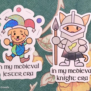 May include: Two stickers featuring cartoon animals in medieval costumes. The first sticker shows a dog dressed as a jester, juggling balls. The second sticker shows a cat dressed as a knight, holding a spear. Both stickers have the text "in my medieval" and then either "jester era" or "knight era".