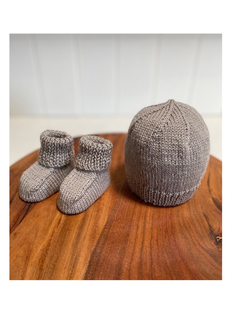 May include: A set of gray knitted baby booties and a matching hat. The booties have a fold-over cuff and the hat is a simple beanie style.