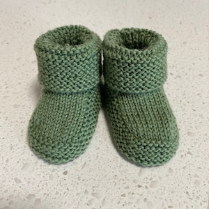 May include: A pair of green knitted baby booties with a folded cuff.