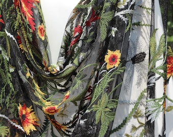 May include: Black sheer fabric scarf with embroidered floral design. The scarf features vibrant red, yellow, and green flowers and leaves. The edges are finished with a delicate, scalloped trim, creating an elegant accessory.