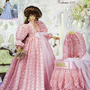 Op de afbeelding: Een pop in een roze gehaakte Victoriaanse jurk met bijpassende muts en wieg. De afbeelding komt uit een haakpatroonboek met de titel "Crochet Collector Costume Volume 112". De pop houdt een kleine teddybeer vast.