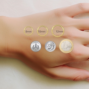May include: Three gold hoop rings with a twisted texture, labeled with diameters of 8mm, 10mm, and 12mm. The hoops are displayed alongside a five pence coin, a US dime, and a one euro coin for scale, with one hoop worn on a finger.