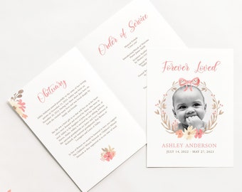 May include: A memorial card featuring a floral wreath design and a photograph of a baby girl. The text reads "Forever Loved" and includes the baby's name, Ashley Anderson, and dates of birth and death: 14 July 2022 - 27 May 2023.