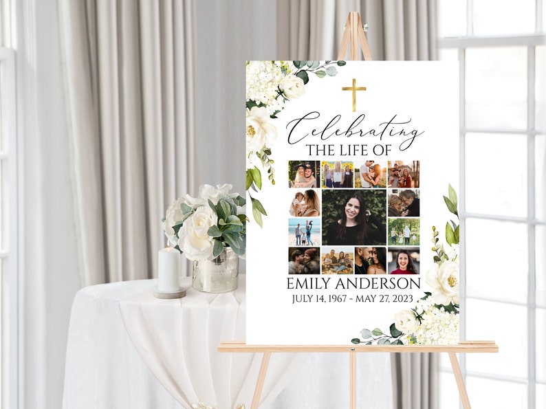 K&ouml;nnte beinhalten: Ein wei&szlig;es Gedenkschild mit einem goldenen Kreuz und einem floralen Rand. Das Schild tr&auml;gt die Aufschrift "Celebrating the Life of Emily Anderson July 14, 1967 - May 27, 2023". Das Schild ist mit einer Fotocollage verziert.